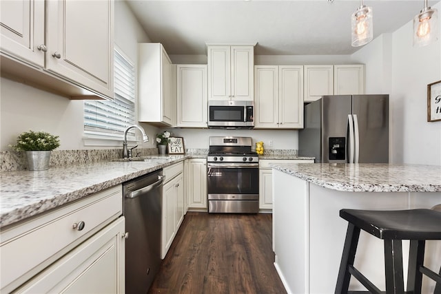 kitchen with dark hardwood / wood-style floors, a kitchen breakfast bar, appliances with stainless steel finishes, hanging light fixtures, and sink