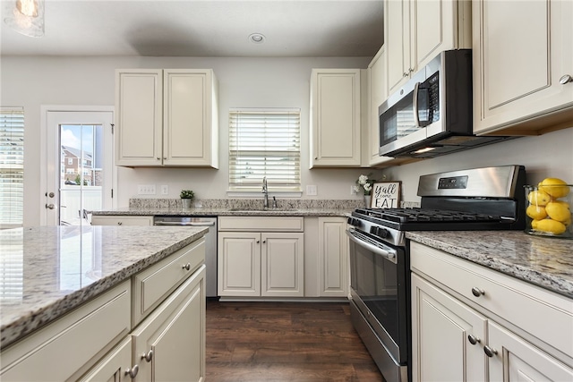 kitchen featuring dark wood-type flooring, stainless steel appliances, sink, light stone counters, and white cabinets