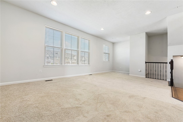 unfurnished room with a textured ceiling and light colored carpet