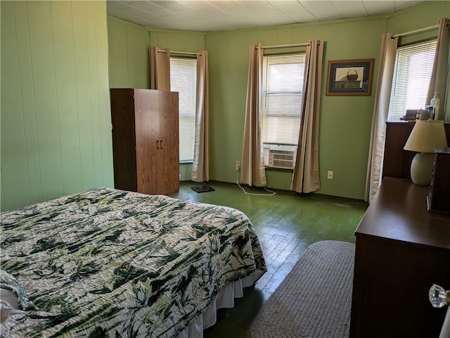 bedroom with multiple windows, cooling unit, and dark hardwood / wood-style floors