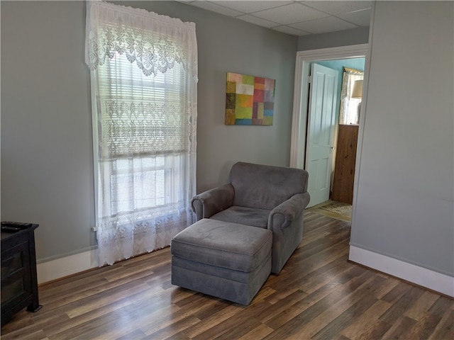 sitting room with a paneled ceiling and dark hardwood / wood-style floors