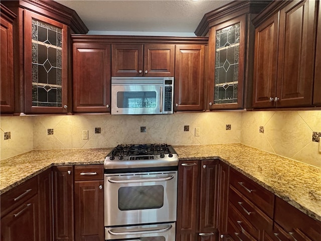 kitchen featuring appliances with stainless steel finishes, light stone counters, decorative backsplash, and a textured ceiling