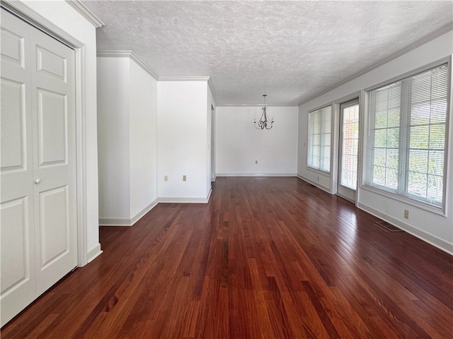 interior space with ornamental molding, a textured ceiling, an inviting chandelier, and dark hardwood / wood-style floors