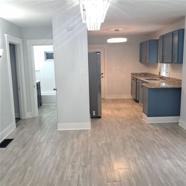 1506 Center St, Wilkinsburg, PA 15221 - kitchen featuring refrigerator, dark stone countertops, light wood-type flooring, and a chandelier