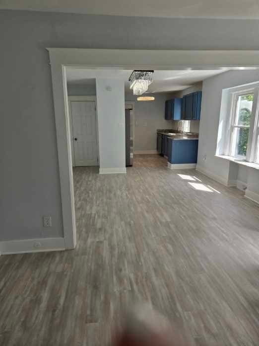 unfurnished living room featuring wood-type flooring and an inviting chandelier