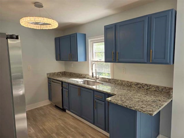 kitchen featuring stone counters, hardwood / wood-style floors, appliances with stainless steel finishes, sink, and blue cabinets