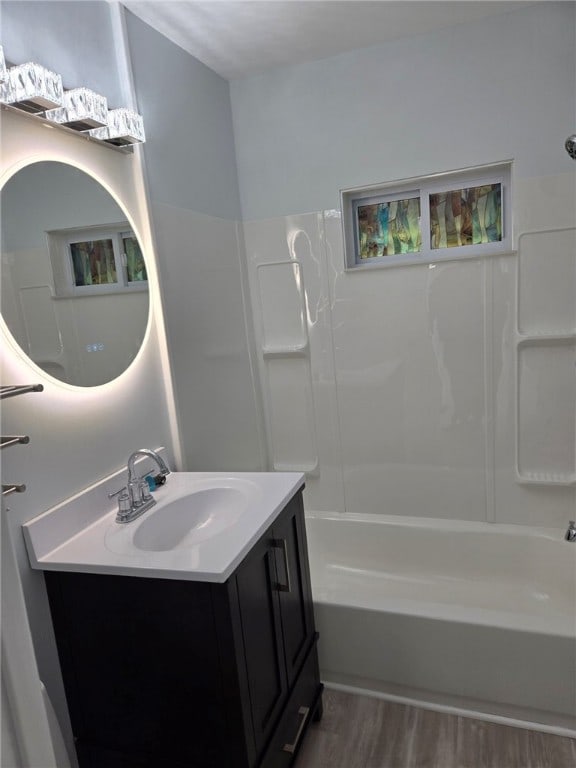 bathroom with vanity, washtub / shower combination, and hardwood / wood-style floors