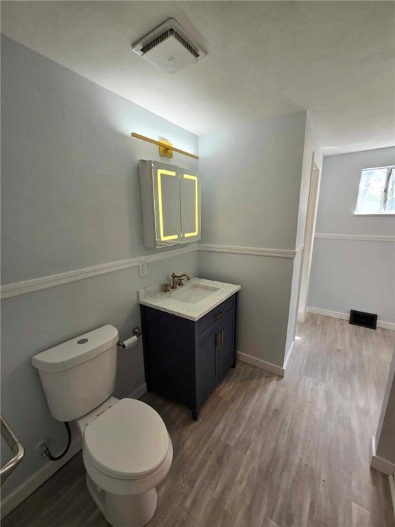 bathroom featuring toilet, hardwood / wood-style flooring, and vanity