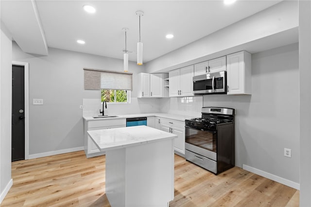 kitchen with light wood-style flooring, appliances with stainless steel finishes, white cabinetry, and a sink