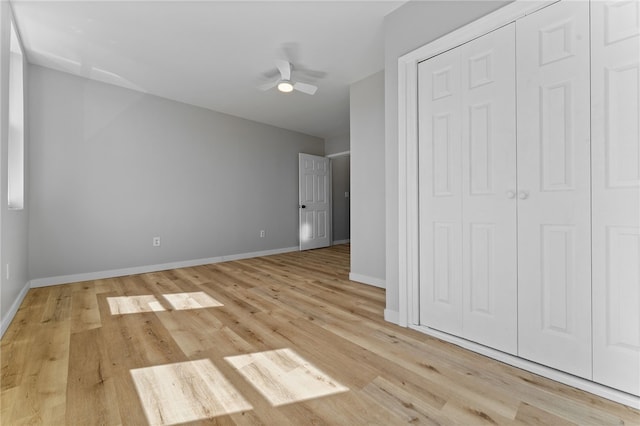 unfurnished bedroom featuring a closet, baseboards, light wood-style flooring, and a ceiling fan