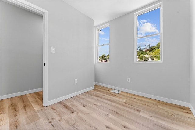 empty room with visible vents, baseboards, and wood finished floors