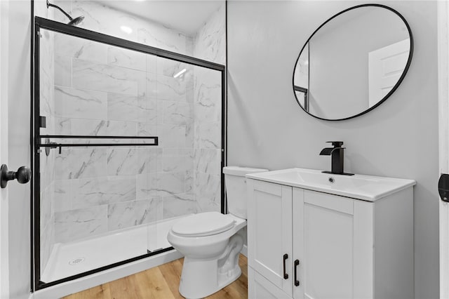 full bath featuring wood finished floors, toilet, a stall shower, and vanity