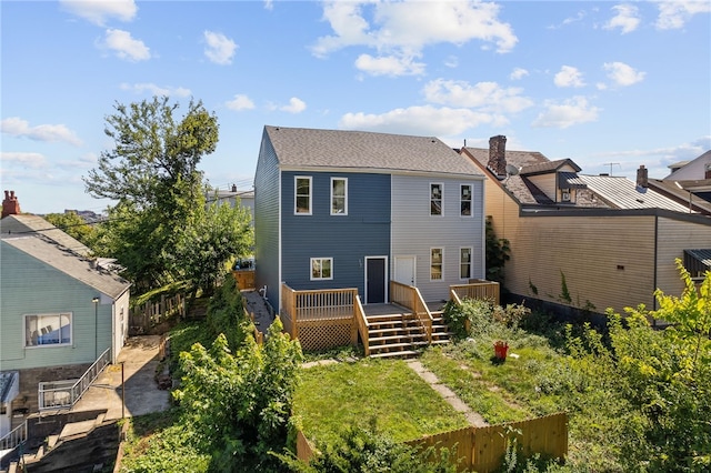 rear view of house featuring a deck, fence, and a shingled roof