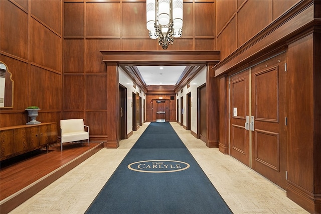 interior space with crown molding, a notable chandelier, light carpet, and wooden walls