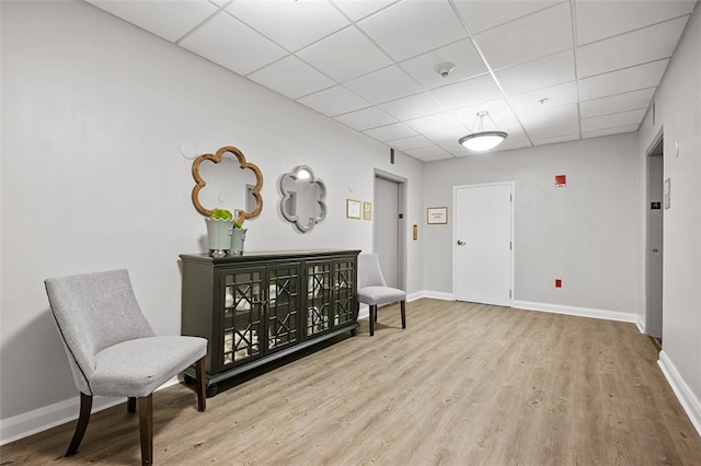 living area featuring light wood-type flooring and a drop ceiling