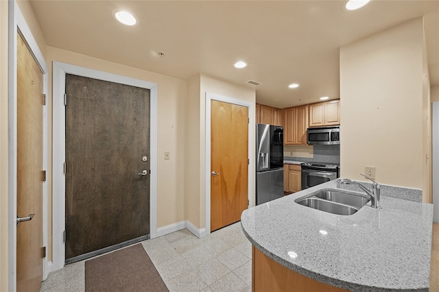 kitchen with light stone countertops, kitchen peninsula, stainless steel appliances, and sink