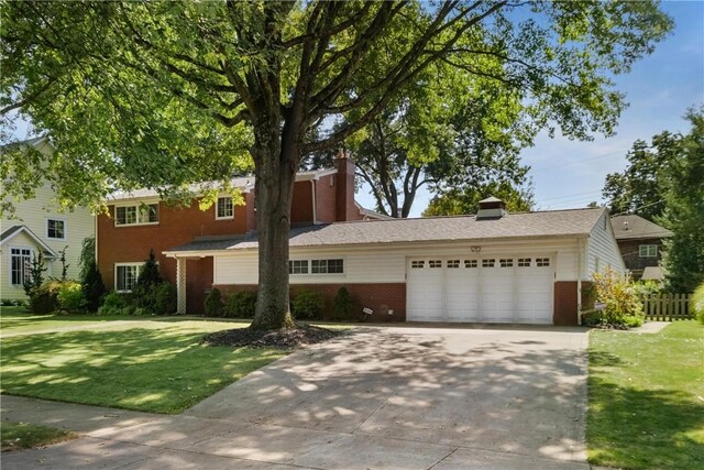 traditional-style house featuring an attached garage, brick siding, a front yard, and concrete driveway