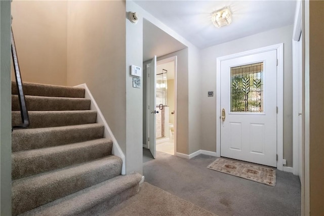 carpeted entryway with baseboards and stairway
