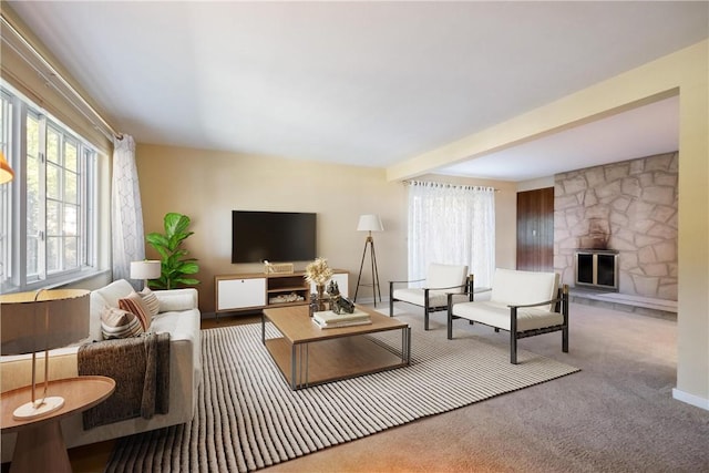 living room with a stone fireplace, beam ceiling, and carpet