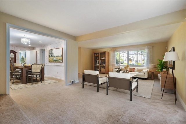 living area with light carpet, a notable chandelier, and baseboards