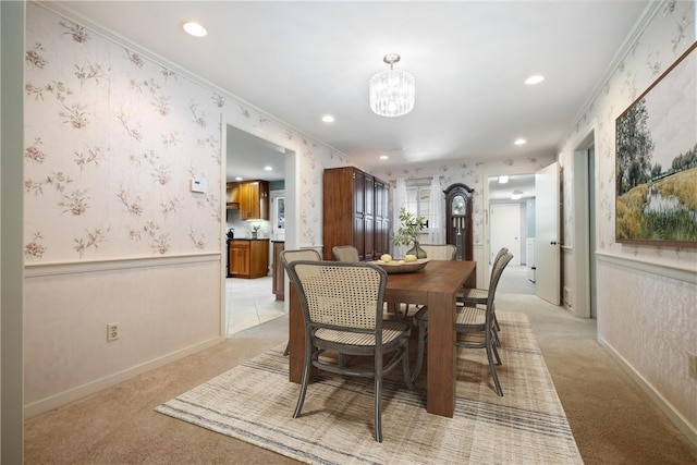 dining area featuring ornamental molding, light carpet, and an inviting chandelier