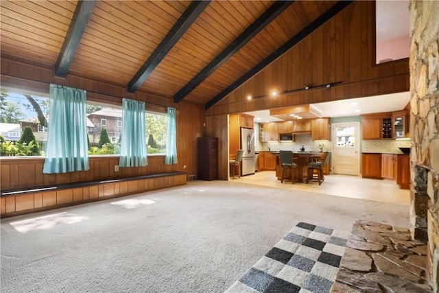 unfurnished living room with high vaulted ceiling, wooden ceiling, light colored carpet, and beamed ceiling