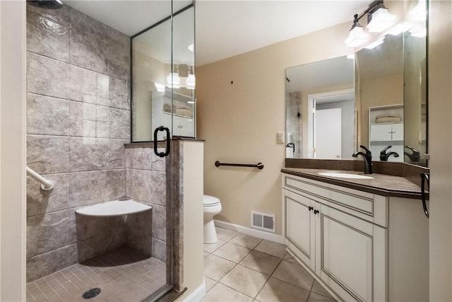 bathroom featuring walk in shower, vanity, toilet, and tile patterned flooring