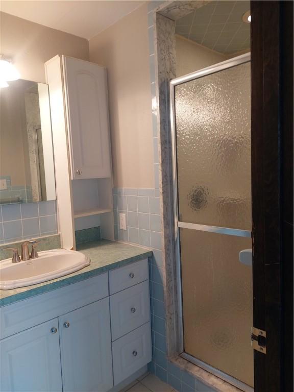 bathroom featuring vanity, tile walls, decorative backsplash, and walk in shower