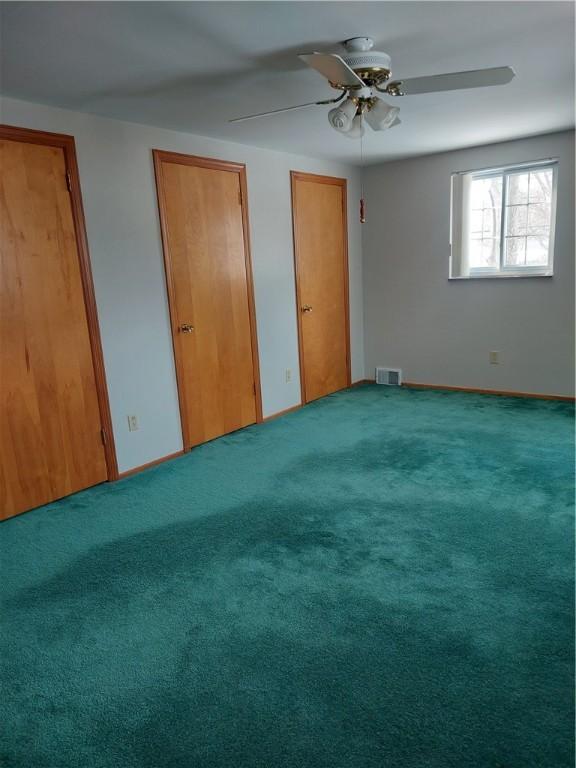 unfurnished bedroom featuring multiple closets, ceiling fan, and carpet flooring