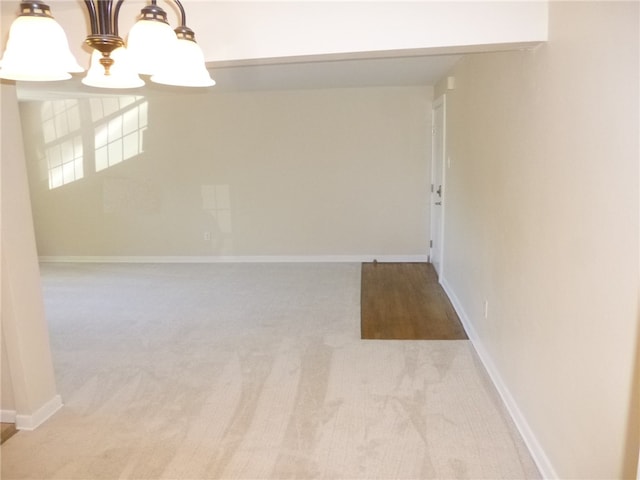 carpeted spare room with a chandelier