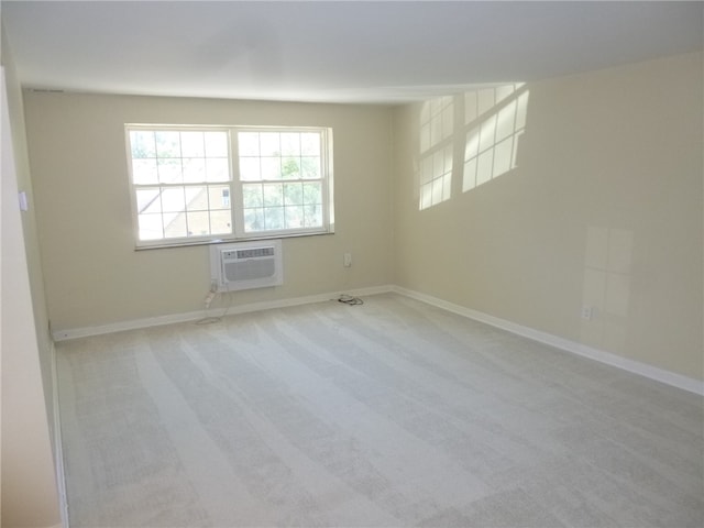 unfurnished room with an AC wall unit and light colored carpet