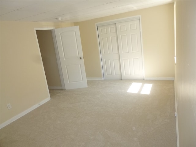 unfurnished bedroom featuring light carpet and a closet