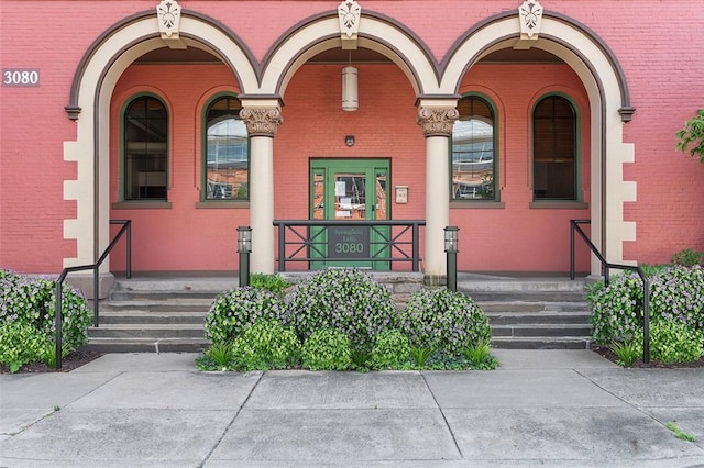 doorway to property featuring covered porch and brick siding