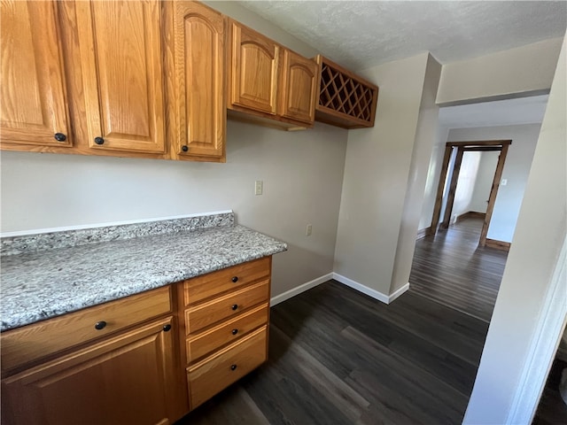 kitchen featuring dark wood-type flooring, a textured ceiling, and light stone counters