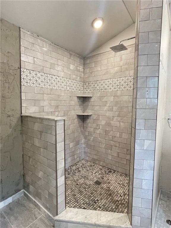 bathroom featuring vaulted ceiling and a tile shower