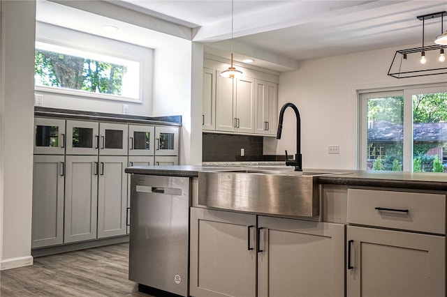 kitchen featuring decorative light fixtures, dishwasher, light hardwood / wood-style flooring, backsplash, and sink