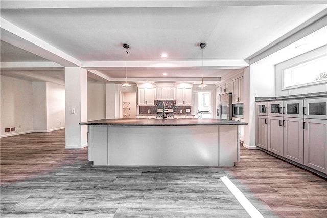 kitchen with pendant lighting, appliances with stainless steel finishes, dark hardwood / wood-style flooring, and a kitchen island with sink