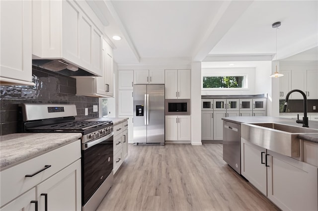 kitchen with white cabinetry, built in appliances, light hardwood / wood-style flooring, sink, and hanging light fixtures