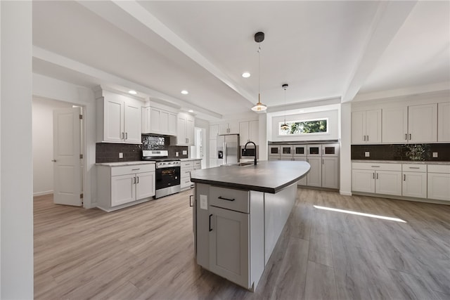 kitchen featuring a kitchen island with sink, appliances with stainless steel finishes, light hardwood / wood-style flooring, and decorative light fixtures