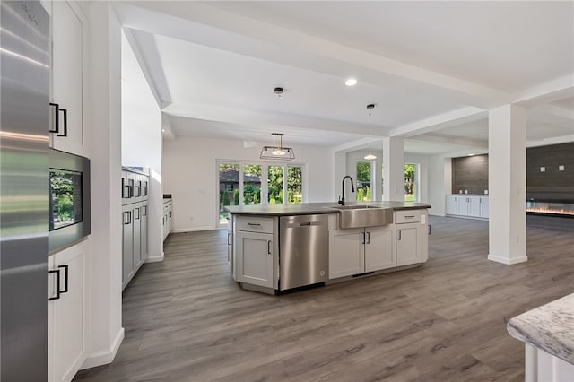 kitchen featuring a fireplace, appliances with stainless steel finishes, hardwood / wood-style floors, and sink