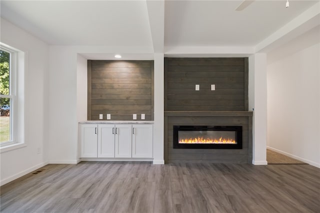 unfurnished living room featuring plenty of natural light, a large fireplace, ceiling fan, and hardwood / wood-style floors