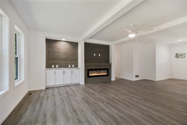 unfurnished living room featuring a large fireplace, ceiling fan, and hardwood / wood-style floors