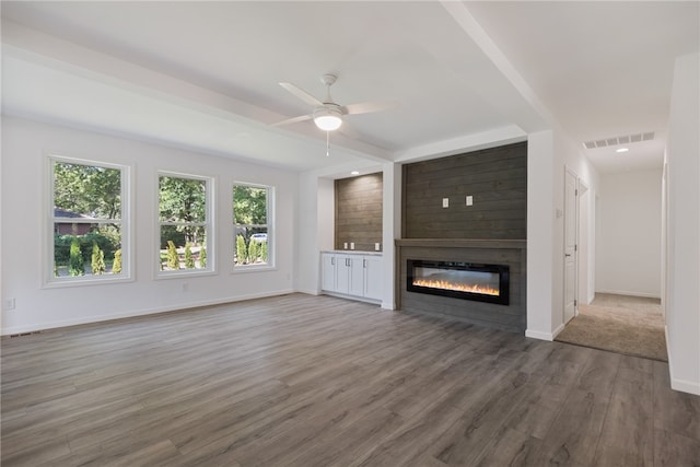 unfurnished living room featuring a large fireplace, ceiling fan, and dark wood-type flooring