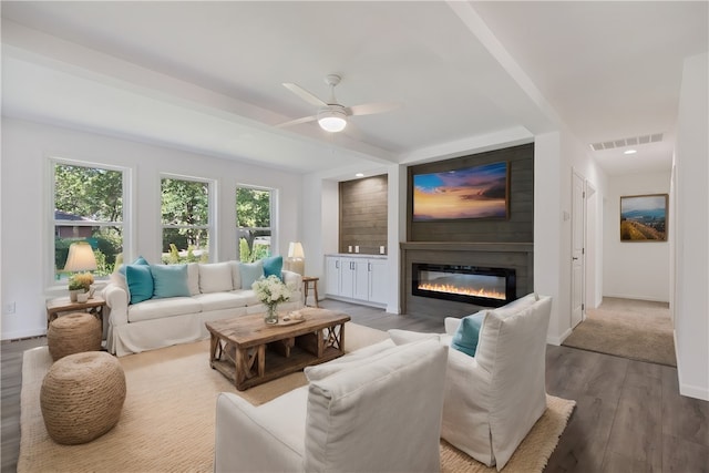 living room featuring hardwood / wood-style flooring, ceiling fan, and a large fireplace