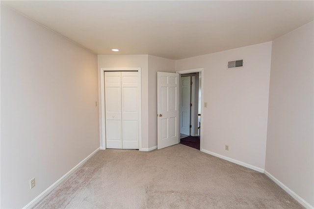 unfurnished bedroom featuring light carpet and a closet