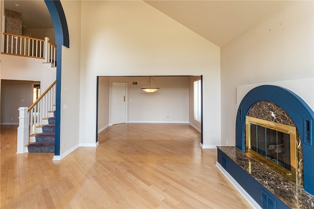 living room with light wood-type flooring, high vaulted ceiling, and a fireplace