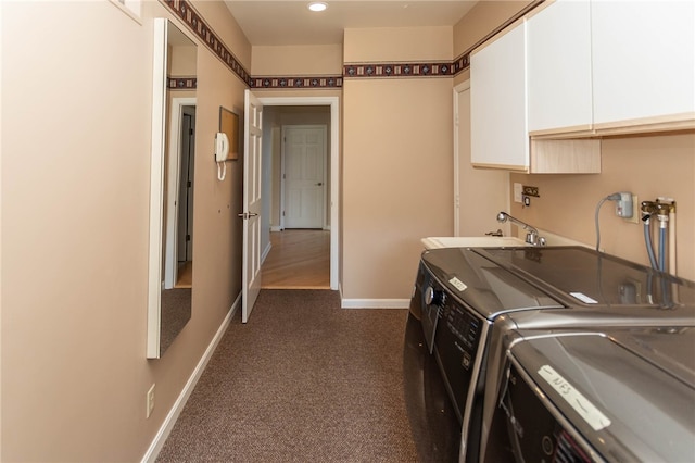 washroom featuring dark carpet, washing machine and dryer, cabinets, and sink