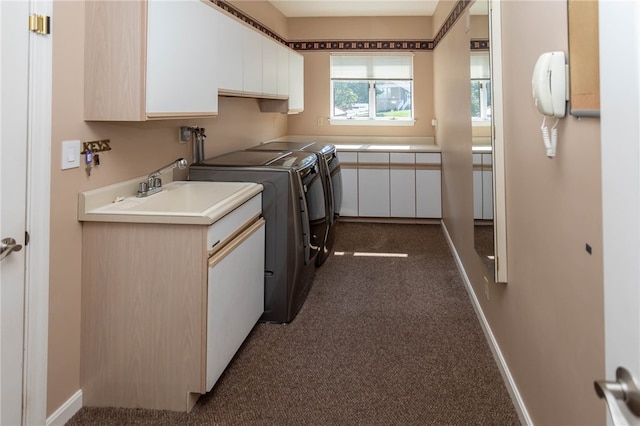 clothes washing area with separate washer and dryer, dark carpet, cabinets, and sink