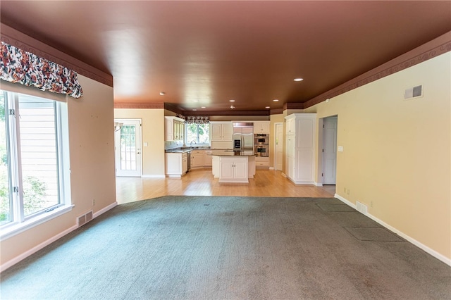 unfurnished living room with plenty of natural light, light hardwood / wood-style floors, and sink