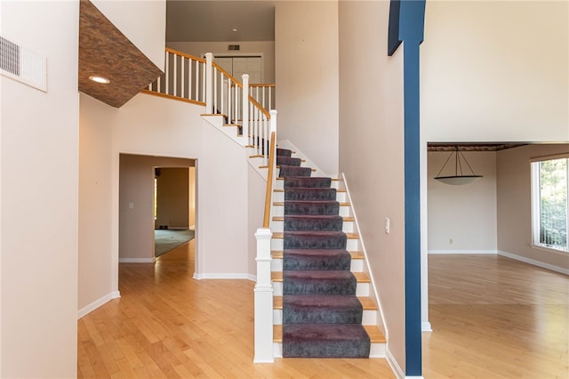 stairway featuring a high ceiling and hardwood / wood-style floors